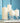 Four white candles in glass holders against a blue wall