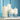 Four white candles in glass holders against a blue wall