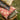 Stack of patterned pillows on a wooden stand outdoors.