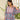 Woman wearing a blue and pink floral blouse with a blurred backgroud.